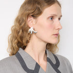 Model wears the Mono Earring Wisley Pink by Mann Studio – a sculptural silver-tone single earring with a bold, organic shape.