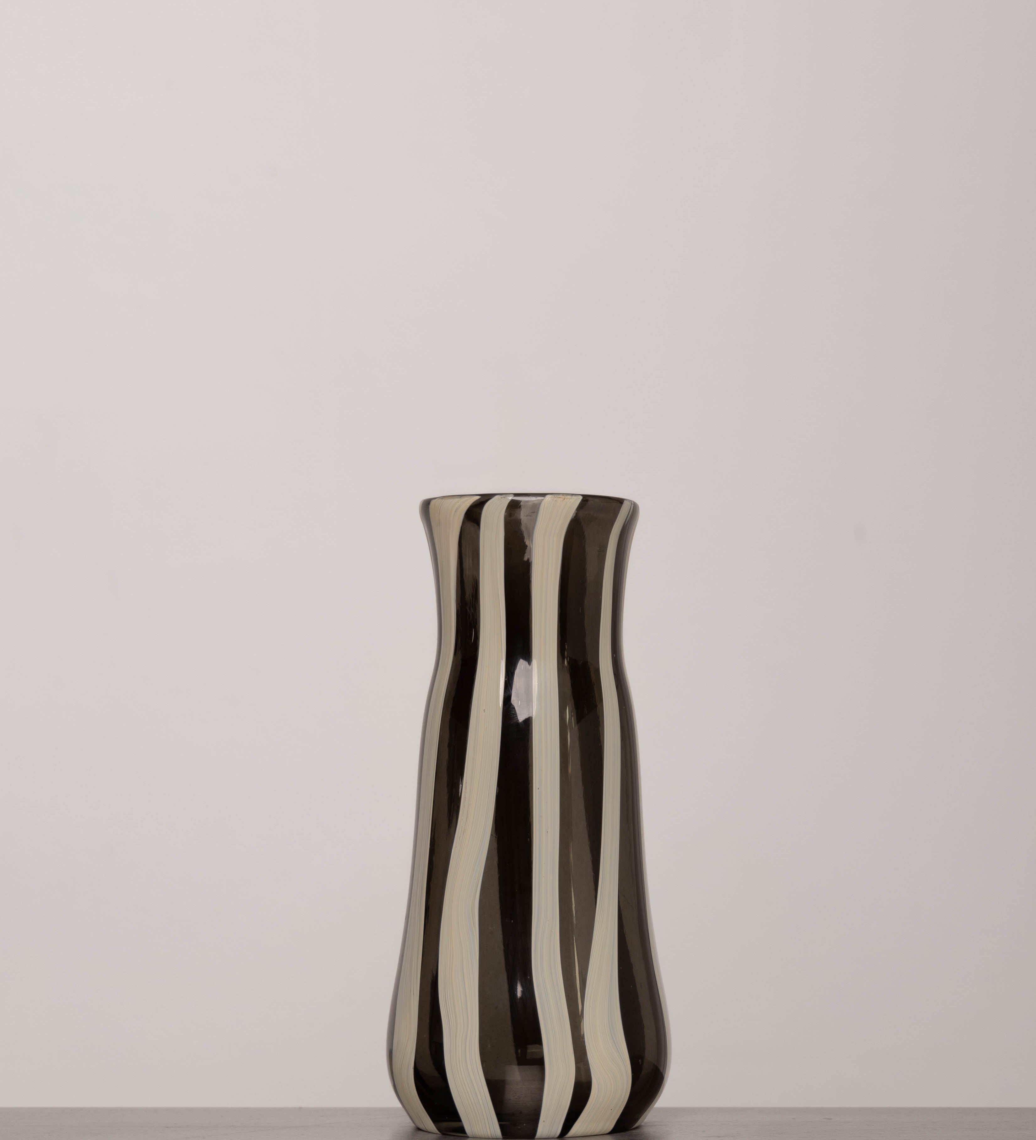 Discover the YAKUSH STRIPS Vase B&W – a 8.6" tall, black-and-white striped handmade recycled glass vase or bottle, ideal for drinks or flowers.