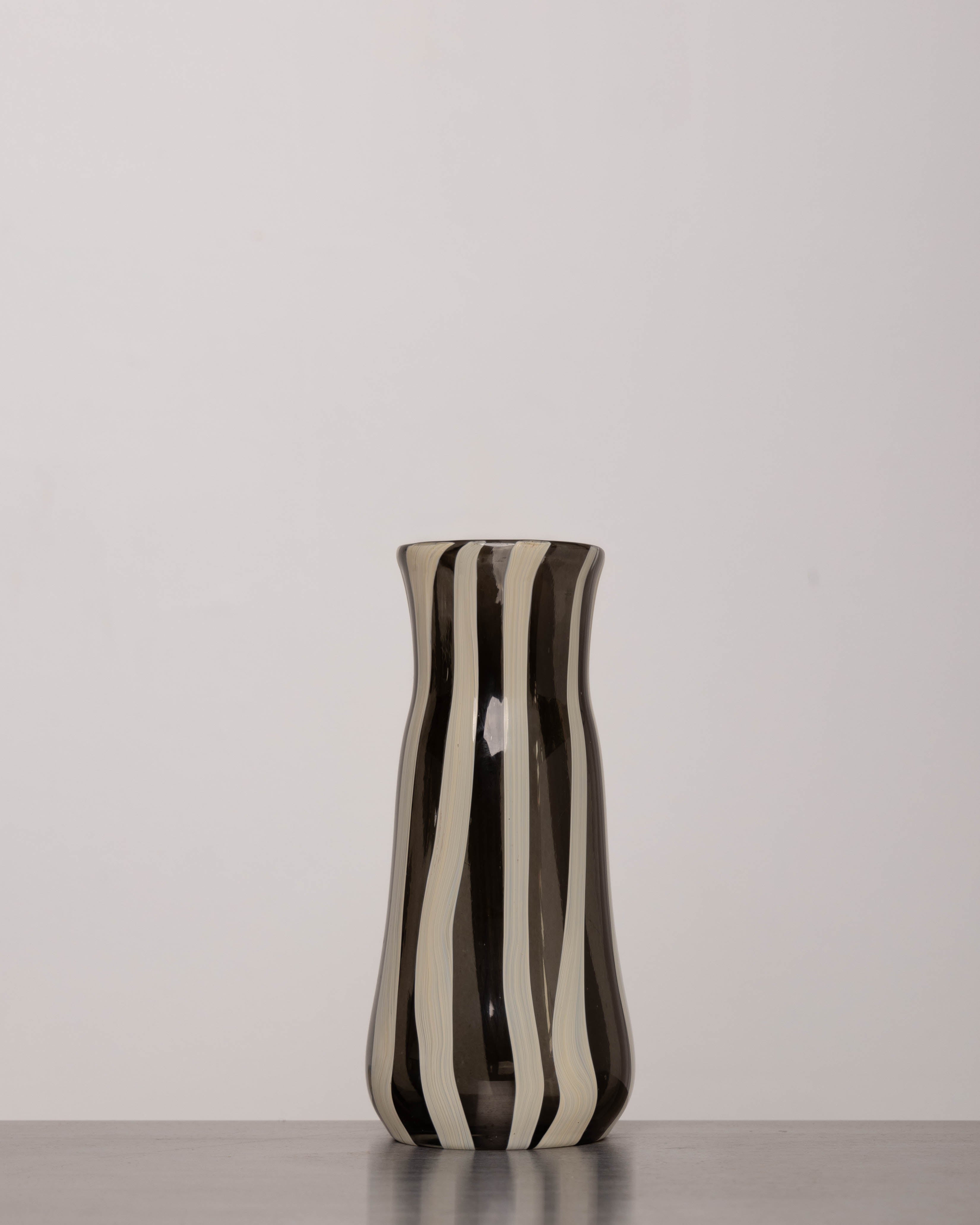 Discover the YAKUSH STRIPS Vase B&W – a 8.6" tall, black-and-white striped handmade recycled glass vase or bottle, ideal for drinks or flowers.