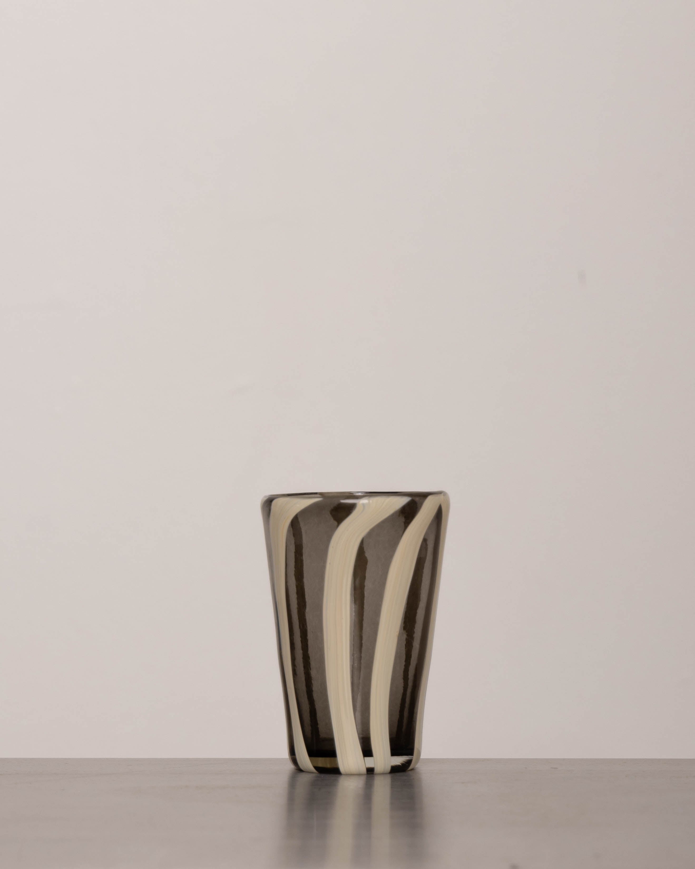 Discover the YAKUSH STRIPS Glass B&W – a 5.3" tall, handcrafted striped glass tumbler made from recycled glass, perfect for summer drinks.